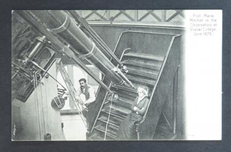 B & W image of a women sitting on a small case, and a man on a latter, next to a large telescope.