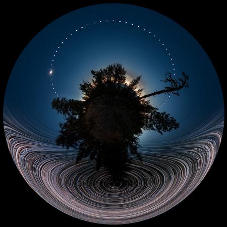 Circular image of eclipse with stars trailing in the sky.