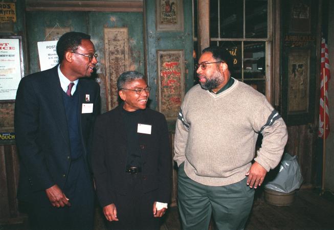 Three people stand in a dark room.