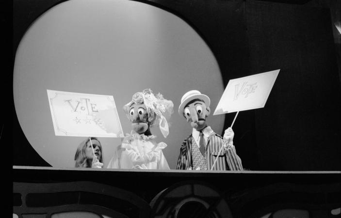 Two puppets holding up posters that read: Vote.