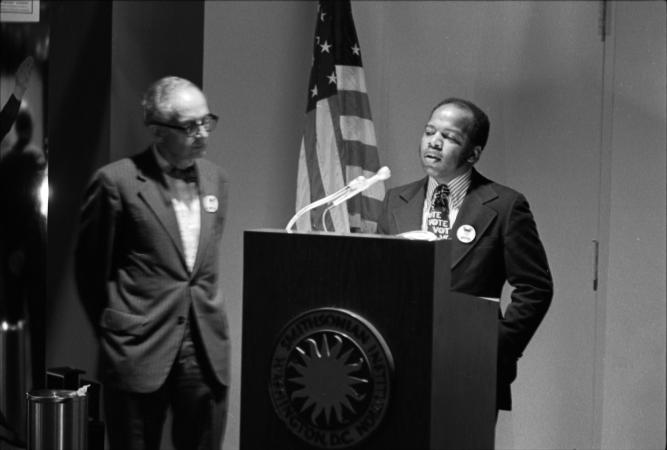 Lewis speaks at a podium.