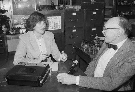 A woman interviewing a man at a table with a recorder in between them. 