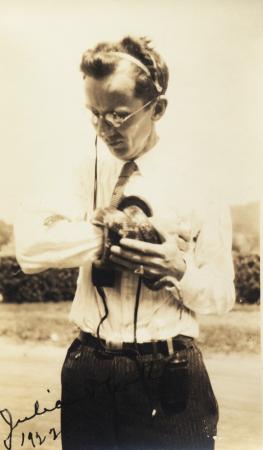 A person wearing wires around their head holds a snake wrapped around one arm. 