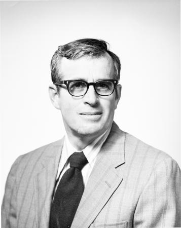 Portrait of Porter M. Kier. He is wearing a suit, tie, and thick-framed glasses.