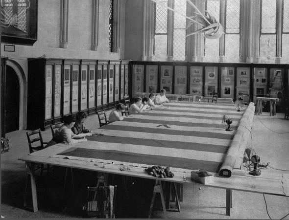 Women at work repairing the Star-Spangled Banner on a set of makeshift tables in the room in the Cas