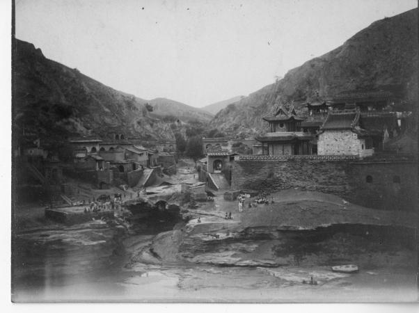 Black and white photograph of a village with various structures on a hilltop.