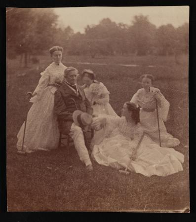 Henry and four women sit and pose in a field.