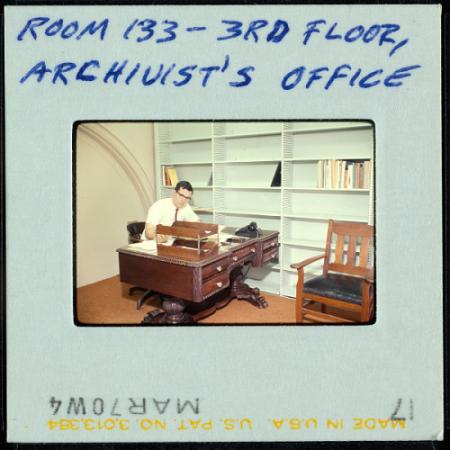 A photo slide of a man sitting at a desk. 