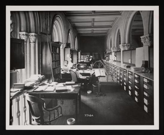 Office space with one man working at the second desk closest to the camera. Books are on the desks. 