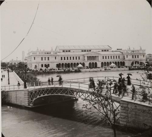 People walk across a bridge. The Woman's Building is in the background.