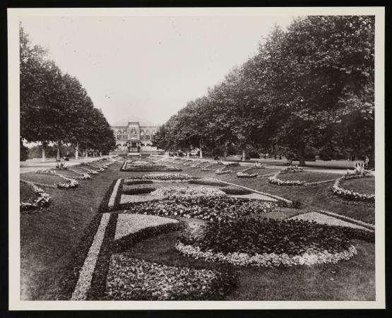 View of the sunken garden with pathways. Tall trees are on either side of the garden patterns. A vie