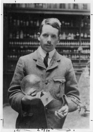 A man stands in a lab holding a glass globe.