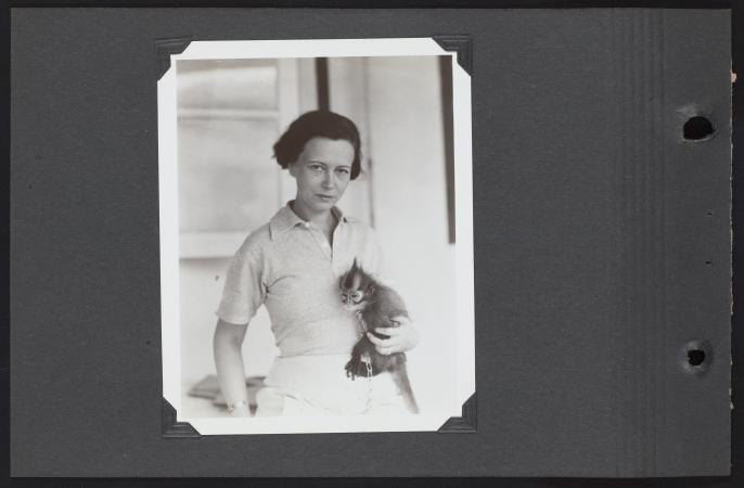 Lucile Mann stares directly into a camera and holds a monkey. 