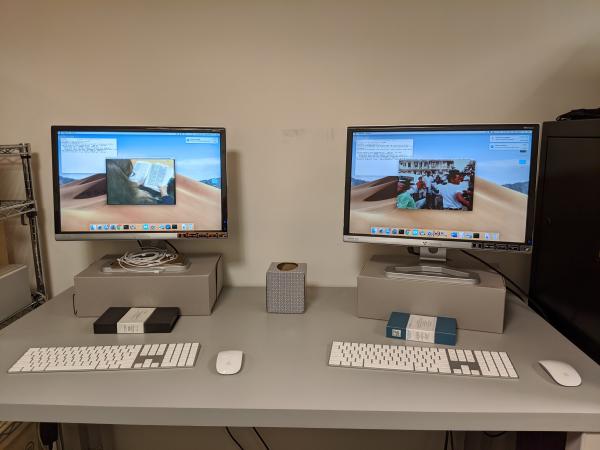 Two computer monitors, keyboards, and mice sitting on a table. A window with text and a screenshot f